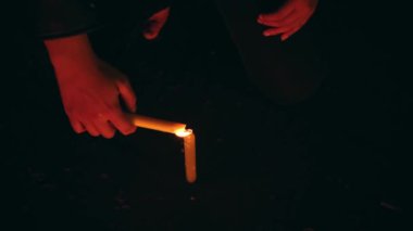 the hands of a woman lighting a candle in the dark before performing a ritual at night