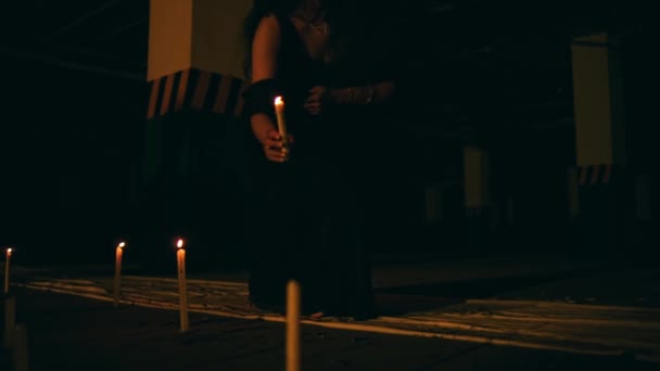 一个黑衣女人正在点着一支蜡烛 蜡烛在黑暗中熄灭 然后在夜间举行恶魔崇拜仪式 — 图库视频影像