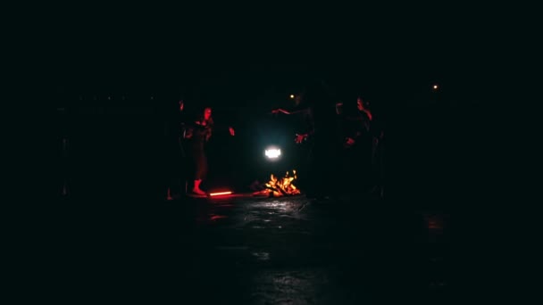 悪魔主義者の一団が夜の暗い場所でたき火の周りで踊り儀式を行う — ストック動画