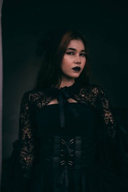 a scary Asian woman with black lips holding her all-black clothes when visiting the cemetery of the deceased
