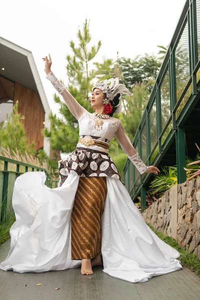 a bride in a white dress is standing in the middle of the bridge with her face full of makeup and a white cloth floating in the air in the morning