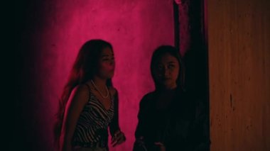 Two hot Asian women are attracted to a handsome man in a night club at night