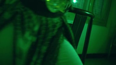 an Asian female dancer dancing in a very sexy dress in front of a mirror in a green room