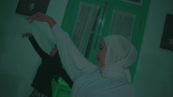 两个身穿白衣和黑衣的穆斯林妇女在一个房间里很有弹性地跳舞 — 图库视频影像