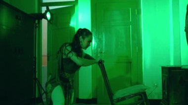 an Asian female dancer dances in a green room with a very sad expression at night