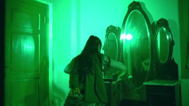an Asian female dancer dances in a green room with a very sad expression at night