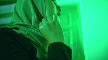 a Muslim woman opens her veil in front of the mirror and dressing table very quietly in her green room