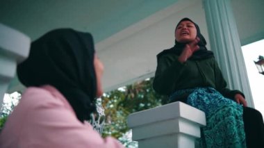 a pair of Muslim women are sitting chatting very exciting in front of the terrace of the house in the morning