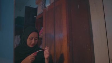 Müslüman bir kadın ayrılmadan önce aynanın önünde makyajını yaparken dudaklarına ruj sürüyor.