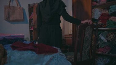 Müslüman bir kadın sabahleyin kahverengi makyaj masasının önündeki makyaj malzemelerini temizliyor.
