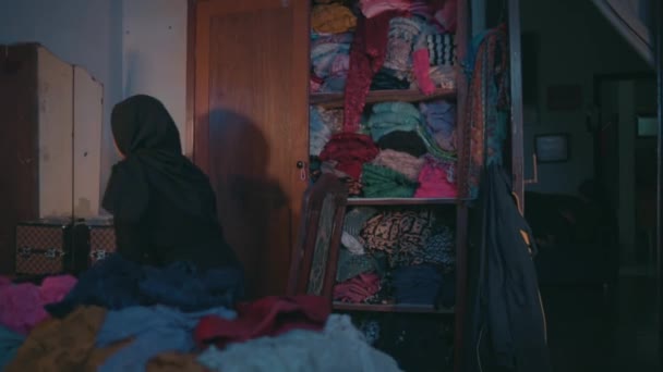一位穆斯林妇女正在打扫房间里散落在床上的脏衣服 — 图库视频影像