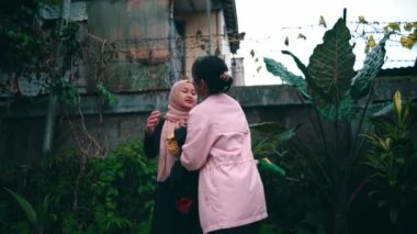 a group of Muslim women hugging each other with distasteful faces in a park in the morning
