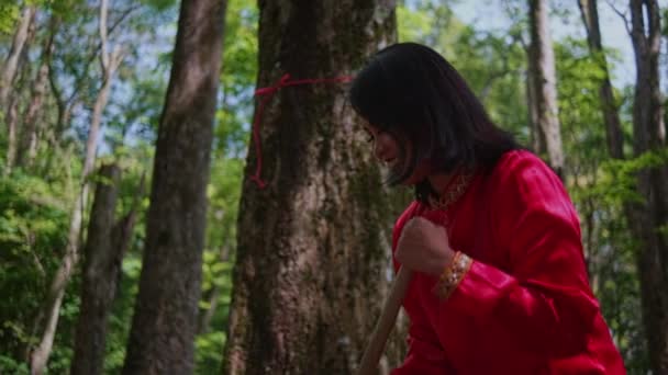 Een Vrouw Met Een Rode Jurk Veegt Grond Het Bos — Stockvideo