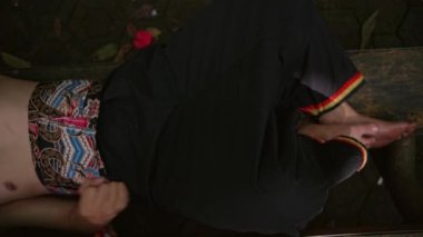 Siyah elbiseli genç bir adam ormanın ortasında üzgün bir şekilde bir bankta yatıyor.