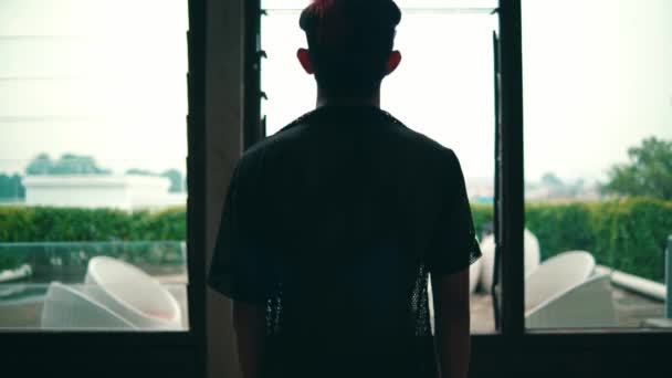 Siyah Tişörtlü Genç Bir Adamın Büyük Bir Pencerenin Önünde Dikilip — Stok video