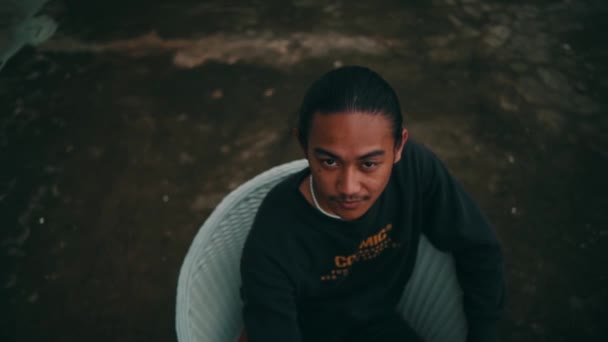 Portret Młodego Azjaty Siedzącego Białym Krześle Patrzącego Kamerę Podczas Wakacji — Wideo stockowe