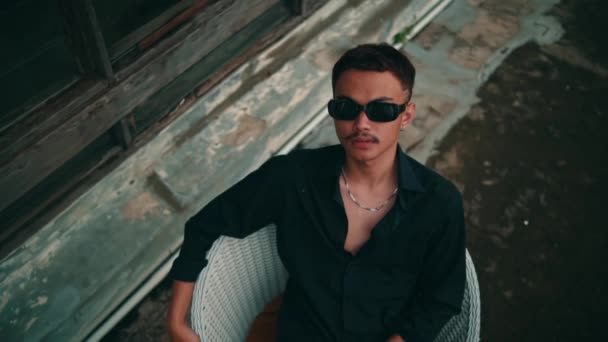 Retrato Jovem Asiático Óculos Pretos Uma Camiseta Preta Sentada Uma — Vídeo de Stock