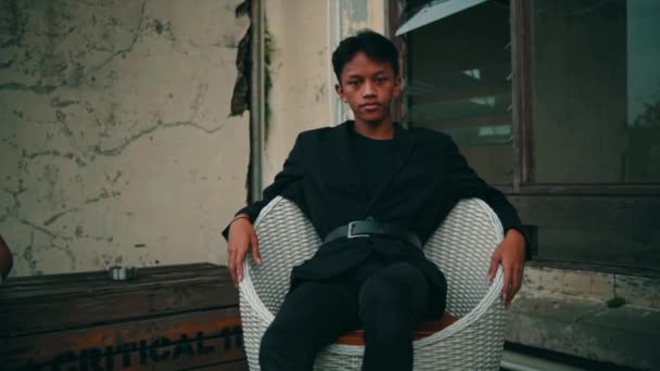 Junger Mann Sitzt Auf Einem Weißen Stuhl Park Unklarer Hintergrund — Stockvideo