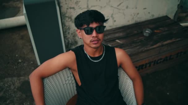 Retrato Jovem Asiático Com Óculos Sol Sentado Uma Cadeira Livre — Vídeo de Stock