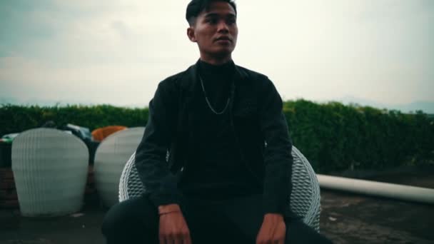 Porträtt Ung Asiatisk Man Svart Jacka Och Kedja Sitter Stol — Stockvideo