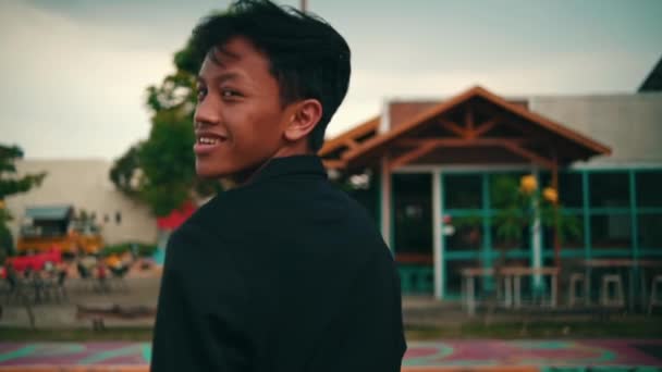 一名身穿黑色外套和太阳镜的年轻亚洲男子在户外篮球场的画像 — 图库视频影像