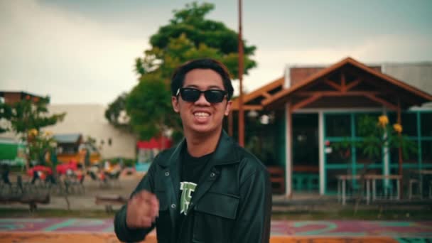 亚洲年轻人放假时带着黑色皮夹克和太阳镜在篮球场 — 图库视频影像