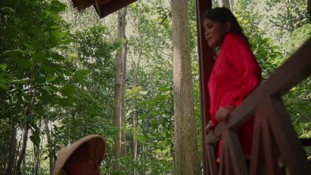 一位穿着红衫的女人站在丛林中的一座木屋里 遇到了一位头戴草帽的男人 — 图库视频影像