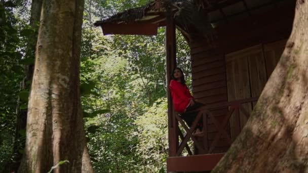 Mladá Žena Červené Bundě Sedí Okraji Dřevěného Balkónu Před Dřevěným — Stock video
