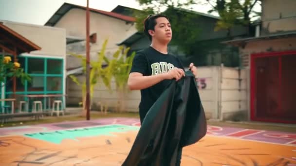 Deri Ceketli Asyalı Bir Adam Öğle Vakti Basketbol Sahasının Ortasında — Stok video