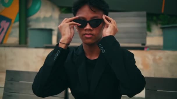 Homem Asiático Terno Óculos Sol Está Sentado Uma Pose Elegante — Vídeo de Stock