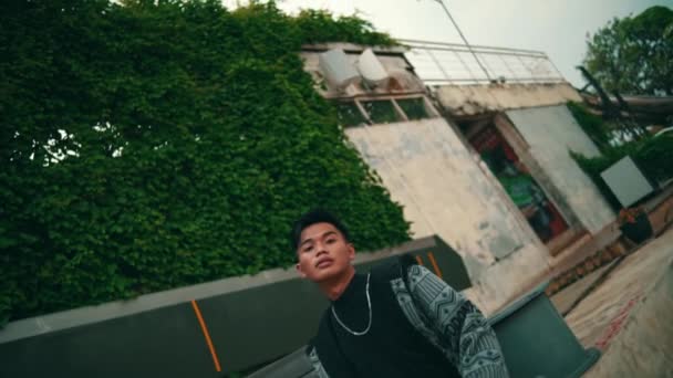 Asiatisk Mand Mønstret Kåbe Sorte Bukser Poserer Stilfuldt Foran Graffiti – Stock-video