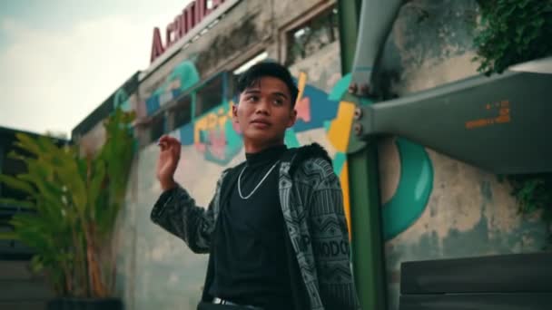 Азиат Узорчатом Халате Черных Штанах Стильно Позирует Перед Стеной Граффити — стоковое видео