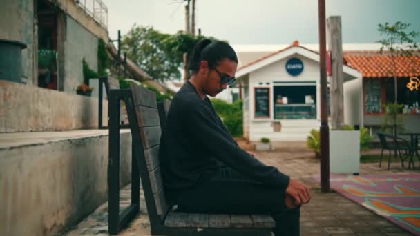 Homem Asiático Calças Rasgadas Uma Camisola Preta Está Sentado Relaxando — Vídeo de Stock