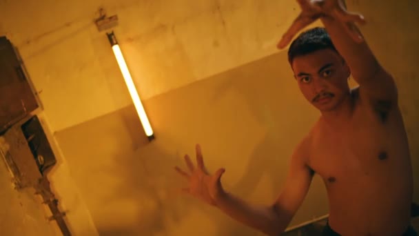 Asijský Muž Tančí Gesty Rukou Nahý Zatímco Hangáru Žlutým Světlem — Stock video