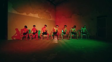 Bir grup insan, gecenin karanlığında neon ışığı olan karanlık bir odada birlikte dans ediyor.