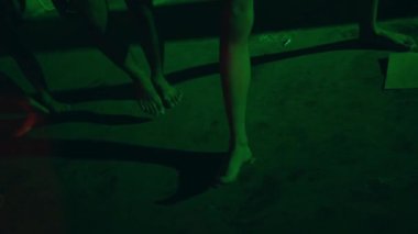 Karanlık odada neon ışıkları olan ve sokak zemininde dans eden genç bir adamın bacaklarını ve ayaklarını kapat.