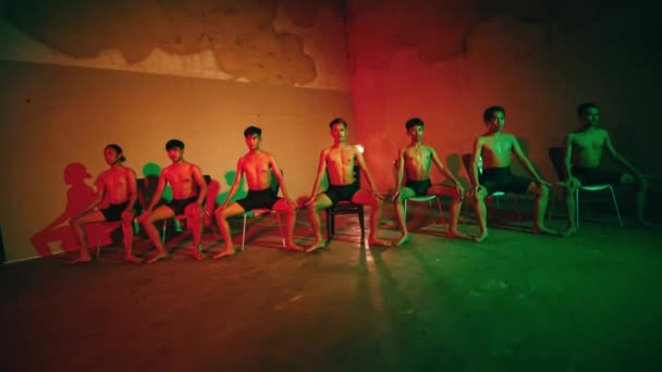 夜にネオンの短いボクサーを着て暗い部屋で一緒に踊るアジアの男性のグループ — ストック動画