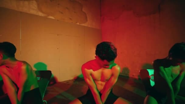 夜の間 赤と緑のライトの部屋の椅子に座っている若者のグループ — ストック動画