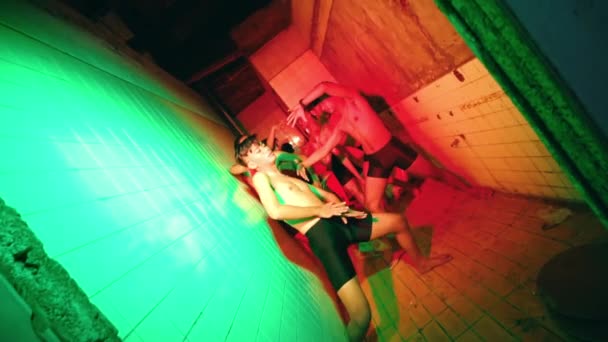 夜にネオンの暗い部屋で踊る裸の胸を持つ若者のグループ — ストック動画