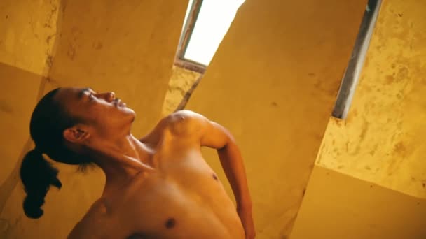 一个绑着头发 赤身裸体的男人 在房间的角落里 用黄灯跳舞 — 图库视频影像