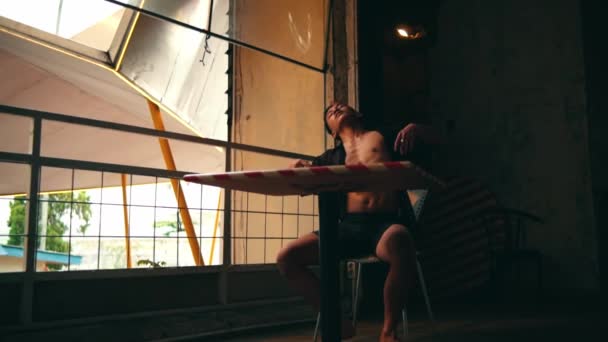 裸の胴を持つ放棄された建物で踊るセクシーアジアの男と日中椅子に座って — ストック動画