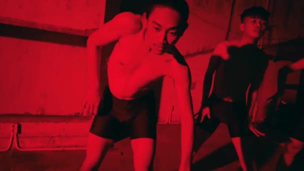 暗い部屋で踊っている赤いランジェリー姿のセクシーな筋肉の男の燃えるようなシルエット ホラー映画 — ストック動画