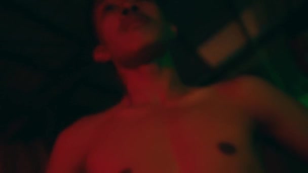 ナイトクラブで裸の胴踊りをするアジア系の男 カラフルな光の効果 — ストック動画