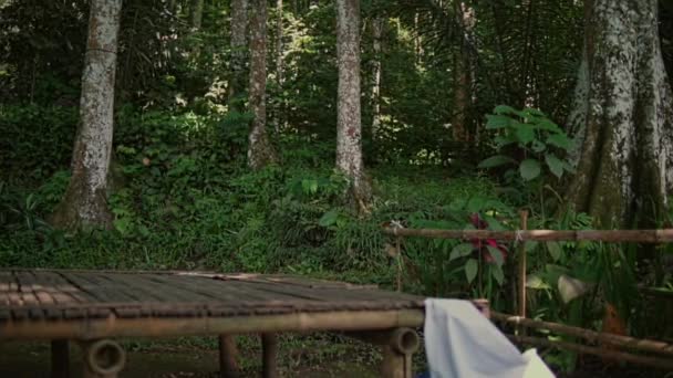 身穿传统泰衣的亚洲年轻人坐在花园旁边的竹桌上 — 图库视频影像