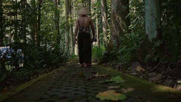 熱帯雨林の道を歩いてわら帽子をかぶったアジア人の男 バックビュー — ストック動画