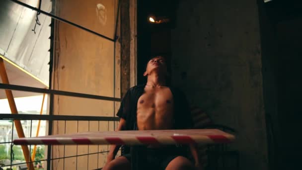 一位性感的亚洲男人在一座废弃的大楼里活动身体时 坐在椅子上 — 图库视频影像