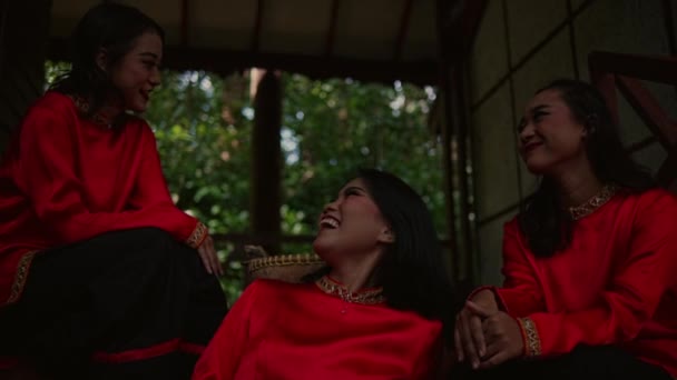 森の中の友人と木製の階段に座っている赤いドレスのタイ人女性のグループ — ストック動画
