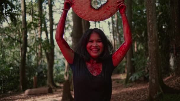 一个疯了的亚洲女人一边笑 一边提起一个在森林中央有一个洞的竹制容器 — 图库视频影像