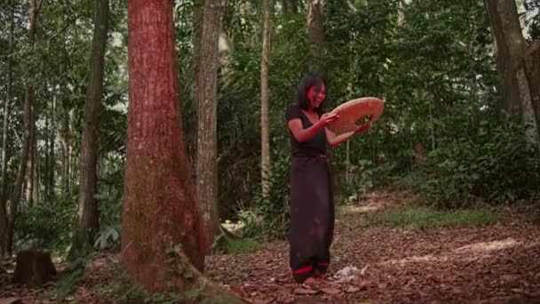 一个疯了的亚洲女人一边笑 一边提起一个在森林中央有一个洞的竹制容器 — 图库视频影像