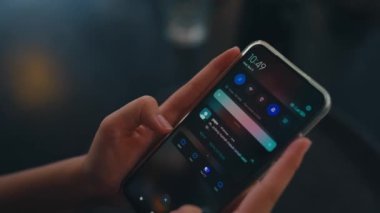 Kafedeki arkadaşından gelen bir mesajı okurken elinde akıllı bir telefon tutan bir kadın.